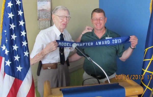 Andy Anderson (l) presents the Model Chapter Award ribbon to Steele at the August meeting.